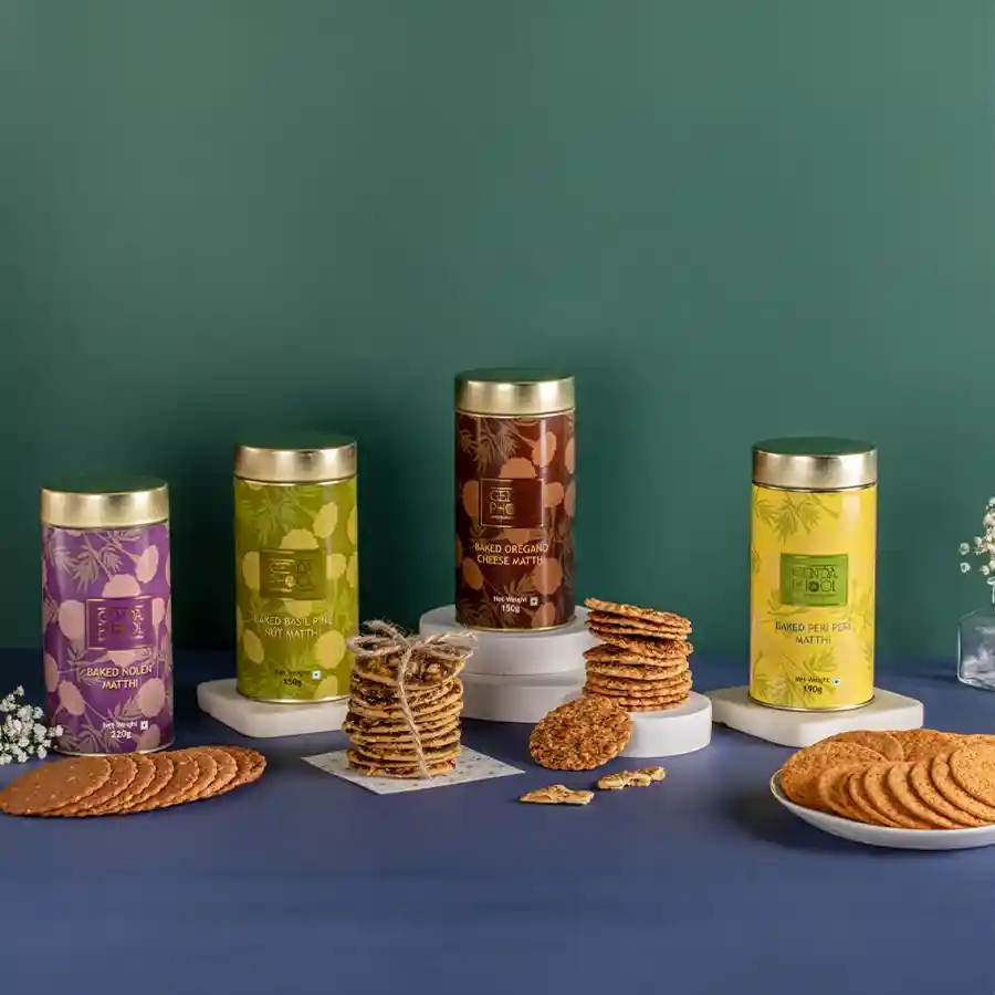 Flavorful Crunch Ode gift box containing four varieties of baked matthi: Peri Peri, Nolen Gur, Oregano Cheese, and Basil Pine Nut.