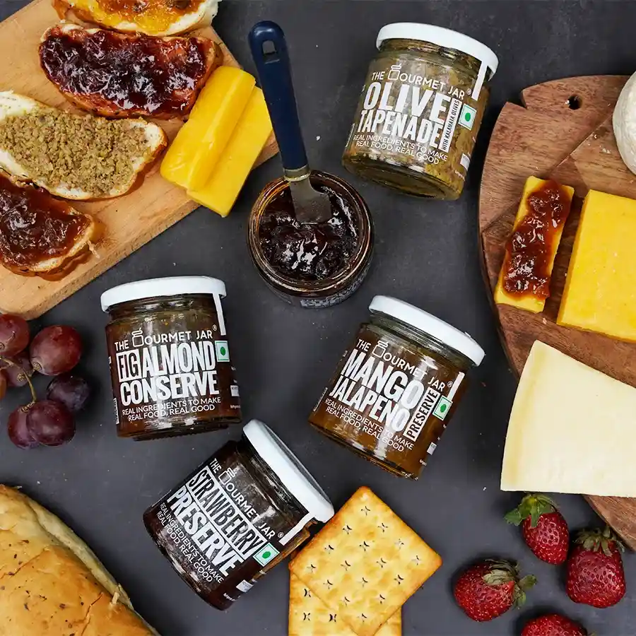 Exquisite Fruit and Olive Preserve Assortment featuring Fig Almond Conserve, Olive Tapenade, Mango Jalapeno Preserve, and Strawberry Preserve.