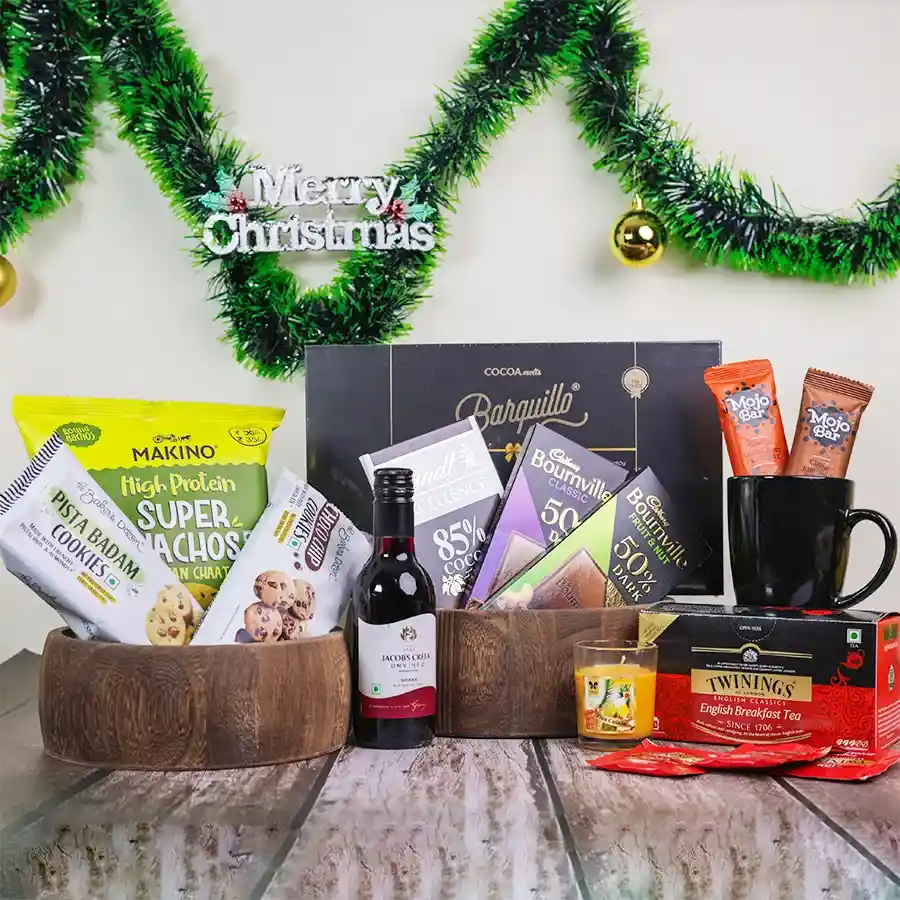 Festive Gourmet Delights Christmas Collection gift basket featuring assorted chocolates, savory snacks, tea, and a cozy candle.