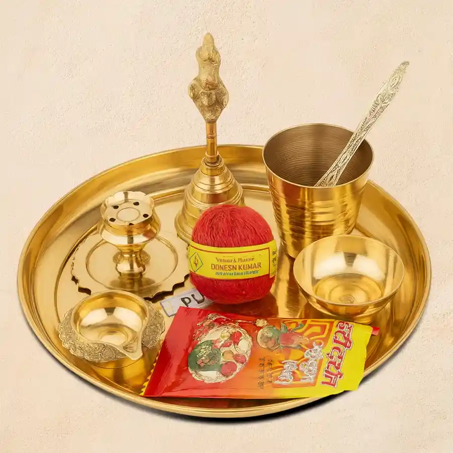 Auspicious puja samagri set in a golden thali, featuring brass diya, bell, roli, kumkum, and more.