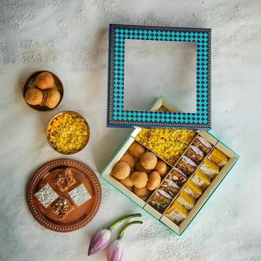 Exquisite Kesar Sweets & Savories Box featuring a variety of treats like Moong Thal, Dodha Barfi, Khatta Meetha Mixture, and Mini Kachori.