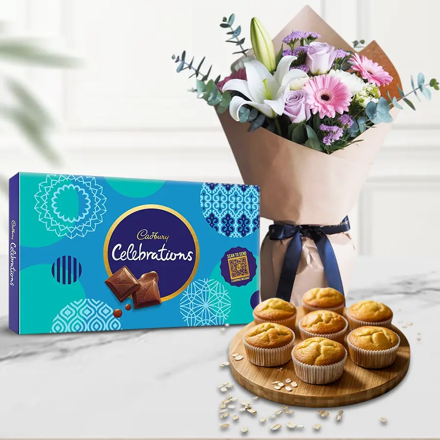 A festive gift set featuring Tutty Fruity muffins, Cadbury chocolates, and a bouquet of seasonal flowers.