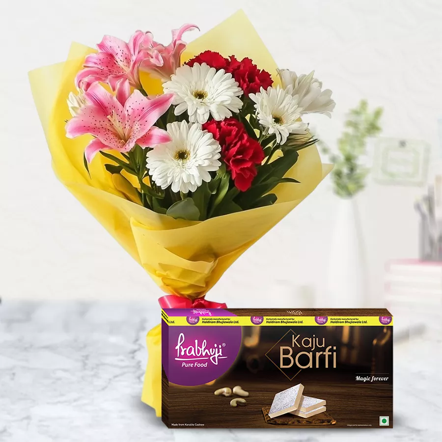A vibrant Seasonal Flowers and Kaju Barfi combo featuring a bouquet of lilies, gerberas, and carnations alongside a pack of Kaju Barfi.