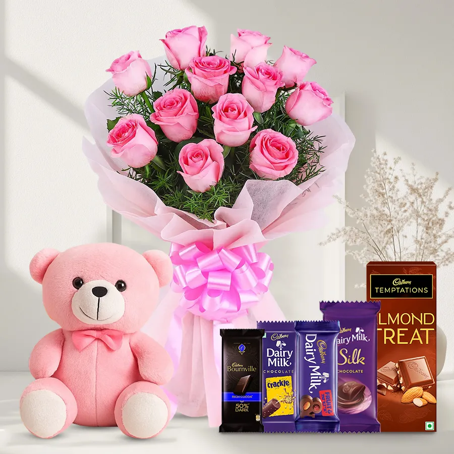 Bouquet of 12 pink roses with a small teddy bear and assorted Cadbury chocolates, including Crackle, Fruit n Nut, Silk, Bournville, and Temptation.