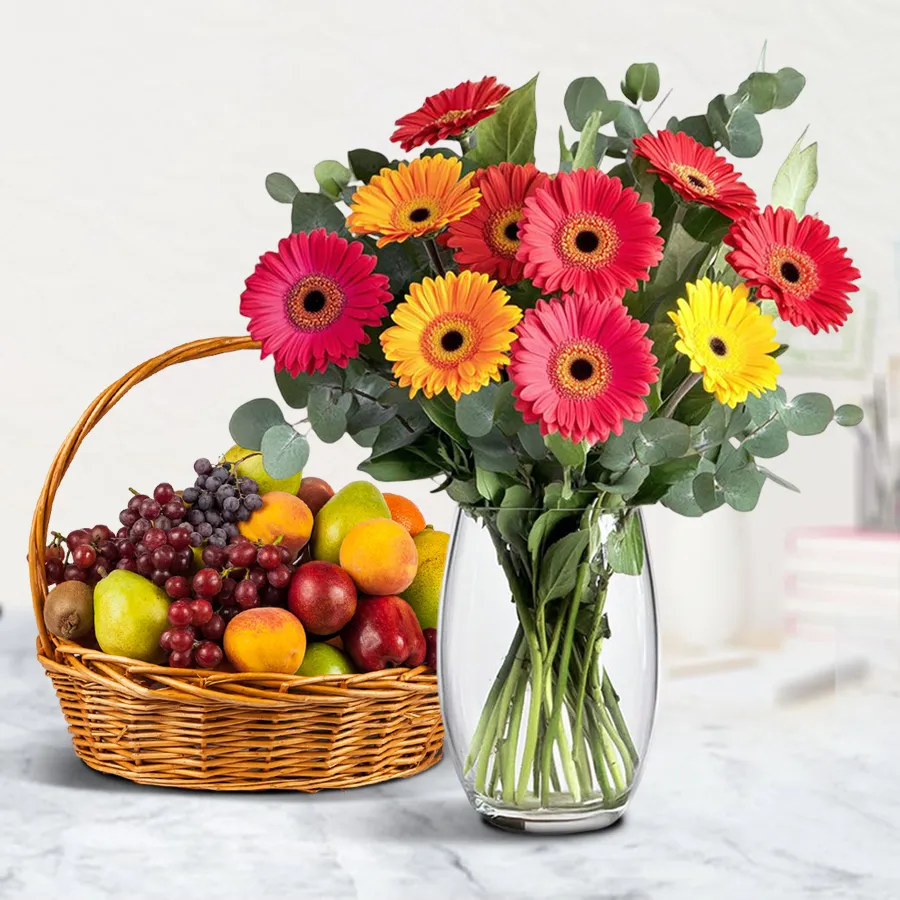 A charming vase filled with 12 mixed gerberas next to a fresh fruits basket, creating a vibrant gift combo.