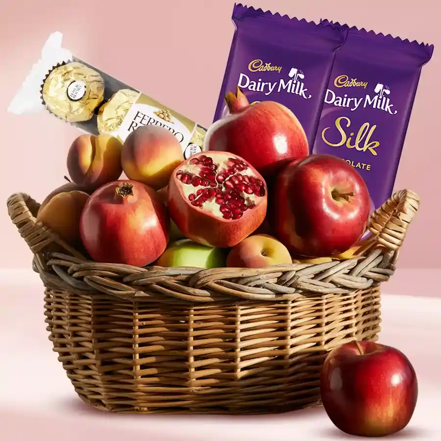 A beautifully arranged gift hamper filled with Ferrero Rocher chocolates, Cadbury Dairy Milk Silk bars, and fresh seasonal fruits.