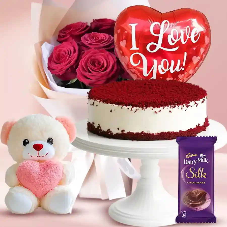 A romantic gift set featuring red roses, red velvet cake, a teddy bear, chocolates, and a balloon.