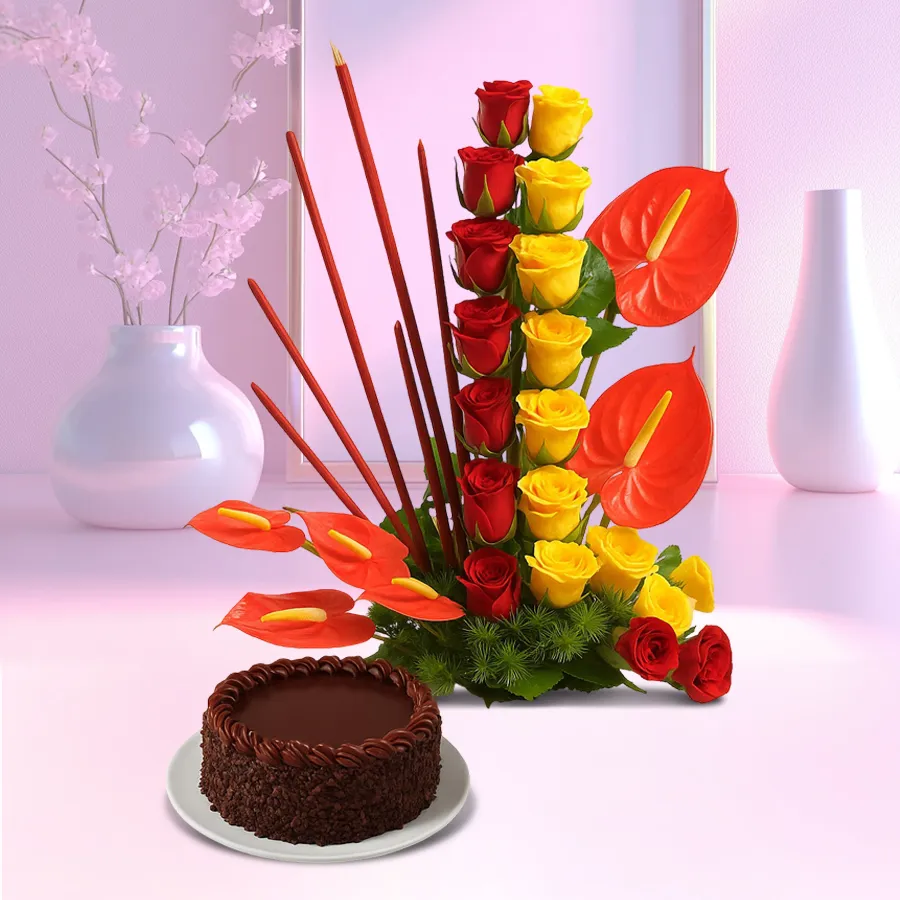 A stunning arrangement of red and yellow roses with red anthurium, accompanied by a rich chocolate cake.