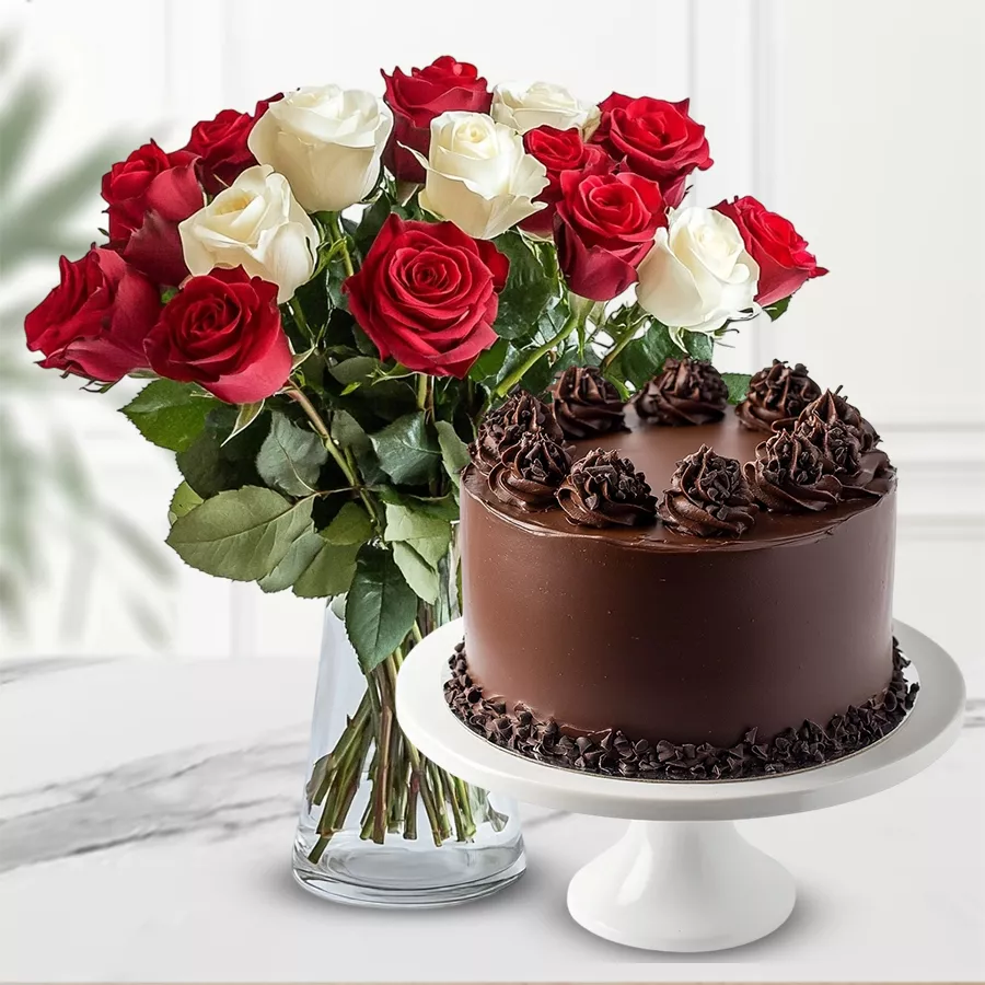 Enticing combo of red and white roses in a vase with a dark chocolate truffle cake.