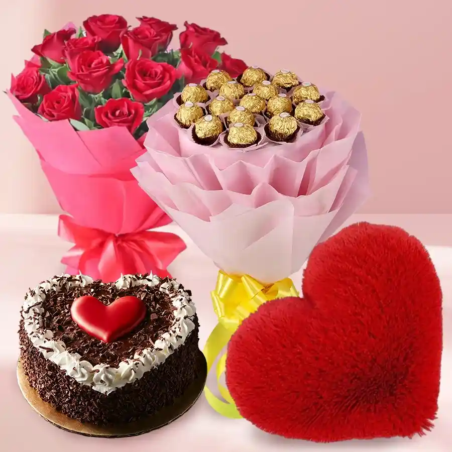 Heartwarming gift combo of red roses, heart-shaped cake, red cushion, and Ferrero Rocher chocolates.