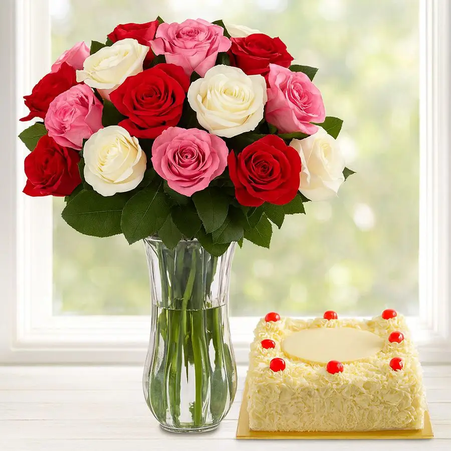 A vibrant arrangement of 18 roses in a vase alongside a square White Forest Cake.