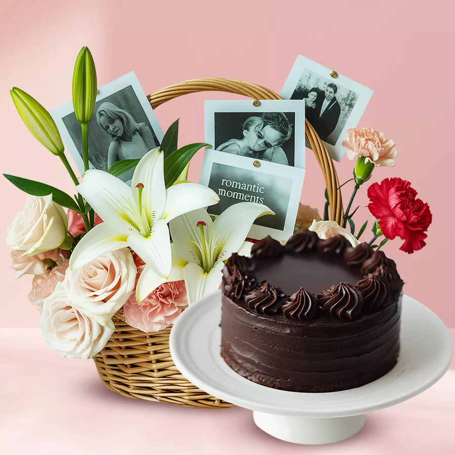 A beautiful arrangement of mixed roses, carnations, a white lily, personalized photos, and a chocolate cake in a charming basket.