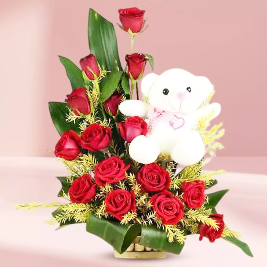 Adorable teddy bear seated in a basket of red roses, perfect for gifting loved ones.
