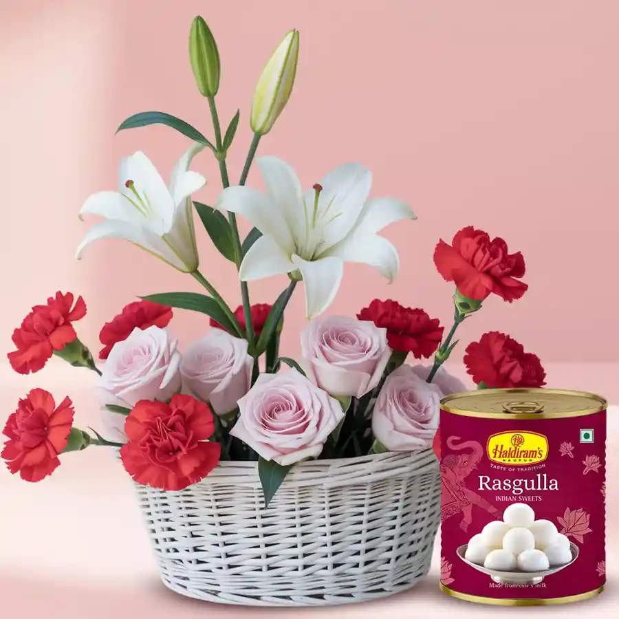 A beautiful mixed flowers basket featuring red carnations, pink roses, and white lilies, paired with a pack of Haldiram Rasgulla.