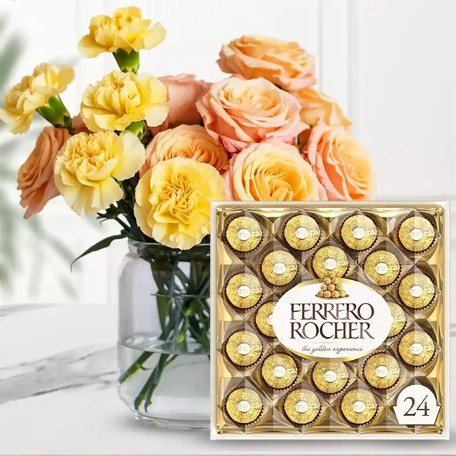 Arrangement of yellow carnations and peach roses in a vase with Ferrero Rocher chocolates.