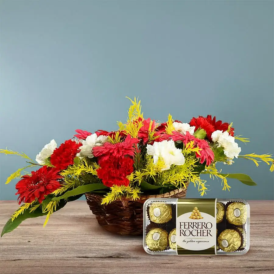 A vibrant basket featuring pink gerberas, mixed carnations, and Ferrero Rocher chocolates, perfect for gifting.