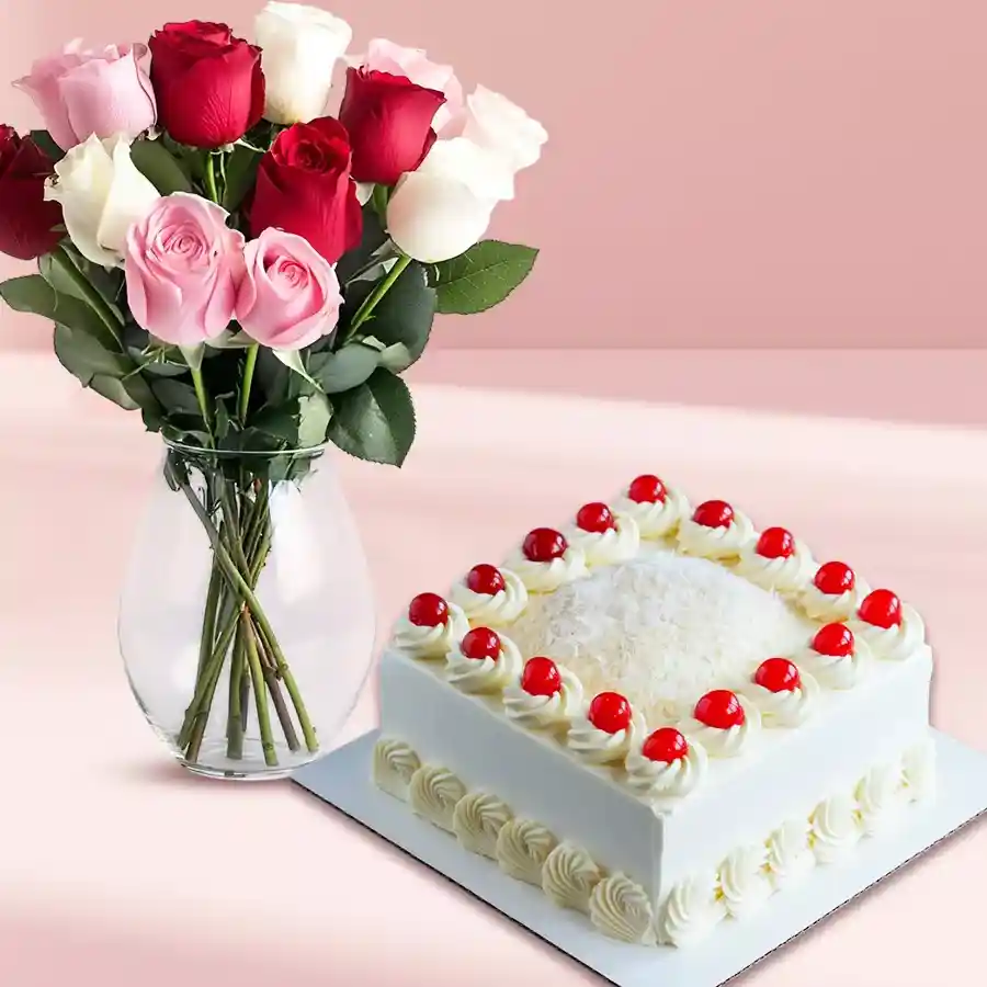 A beautiful display of mixed roses in a glass vase alongside a square eggless White Forest cake.
