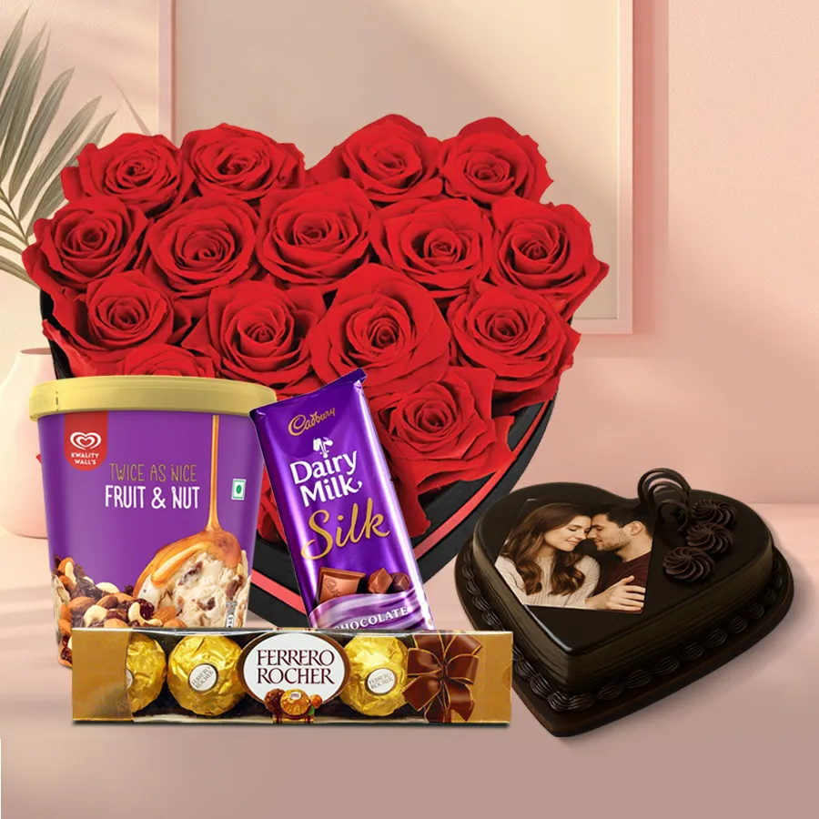 Heart-shaped arrangement of red roses with ice cream, photo cake, and chocolates for a romantic gift surprise.