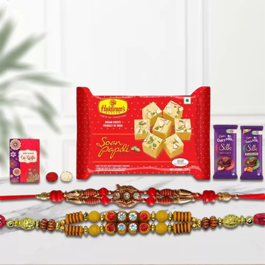 Exquisite festive gift hamper featuring sweets, chocolates, a family Rakhi set, and Roli Tilak Chawal, elegantly arranged for celebrations.