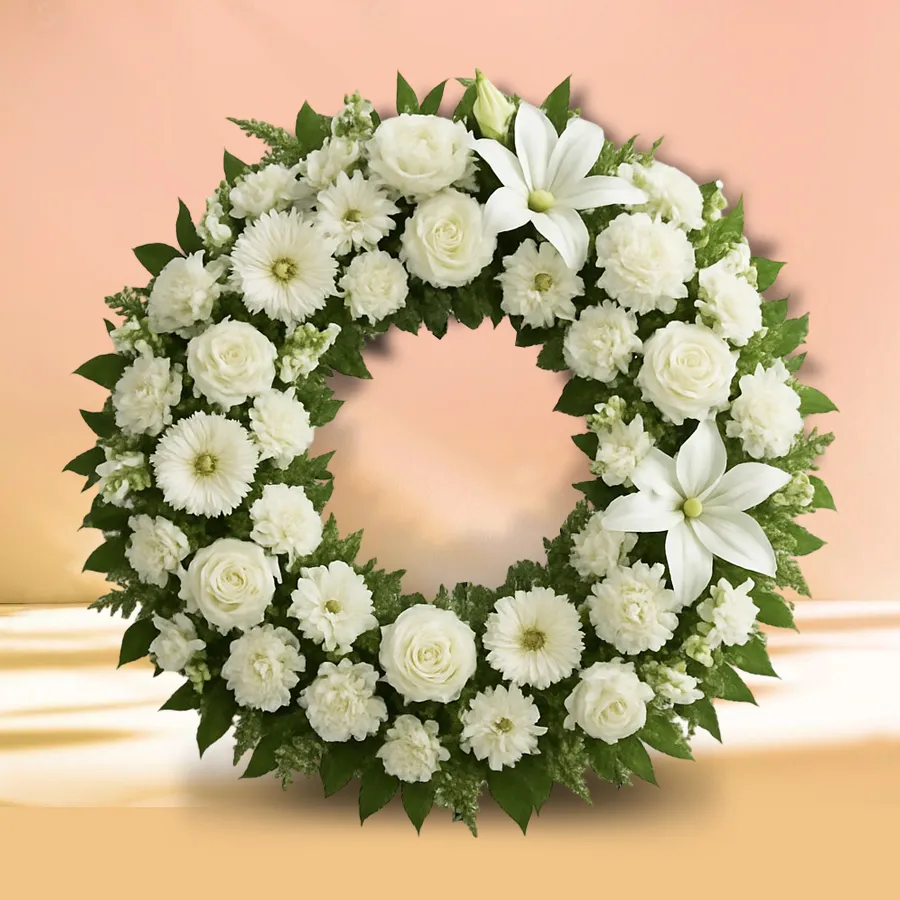 Elegant white sympathy wreath with carnations, roses, and lilies.