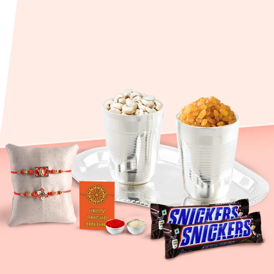 Delicious dry fruits hamper in silver-plated glasses and tray with Snickers, designer Rakhis, personalized message card, and Roli Tika Chawal.