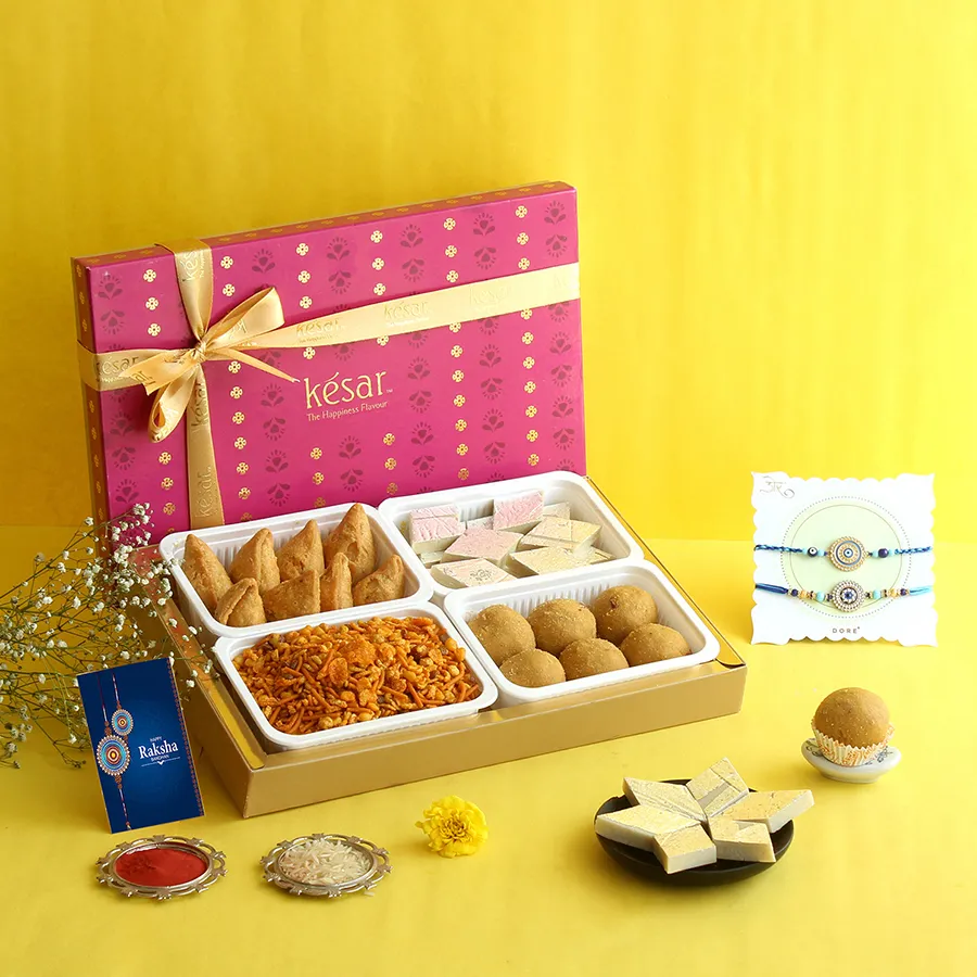 Blissful Rakhi Treats Collection featuring sweets, savory snacks, and Blue Evil Eye Rakhis in a red metal gift box.