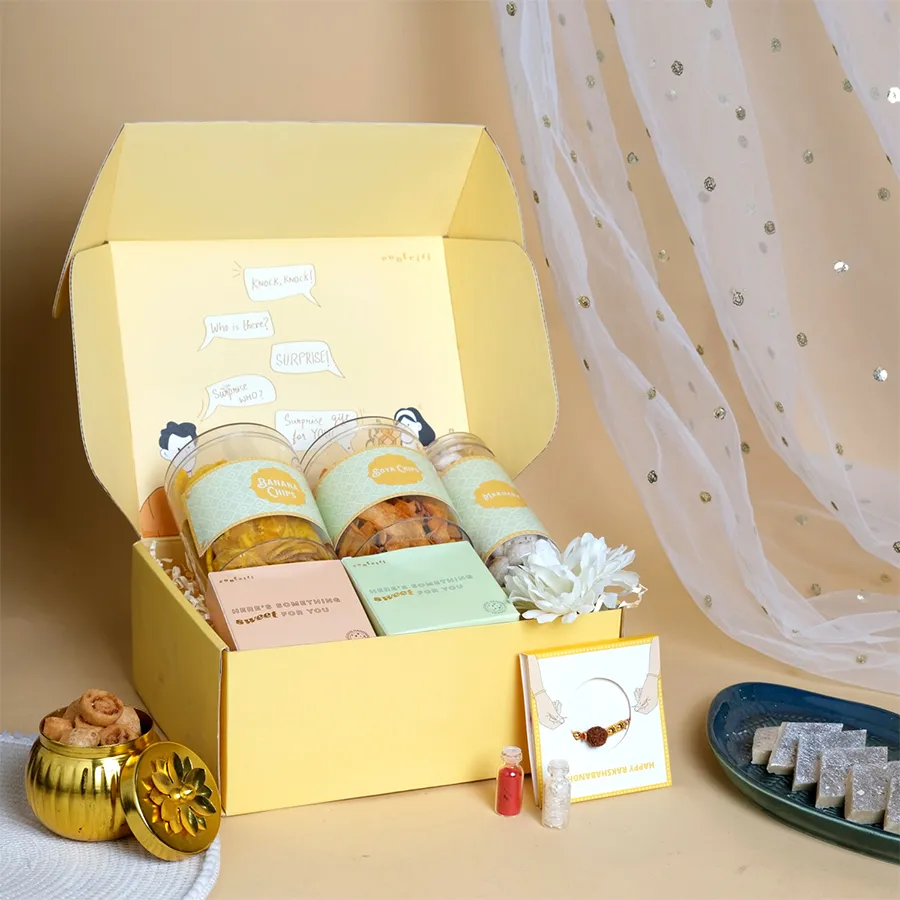 Festive Rakhi and Treats Surprise Pack with Rudraksha Rakhi, snacks, and cookies in a yellow box.