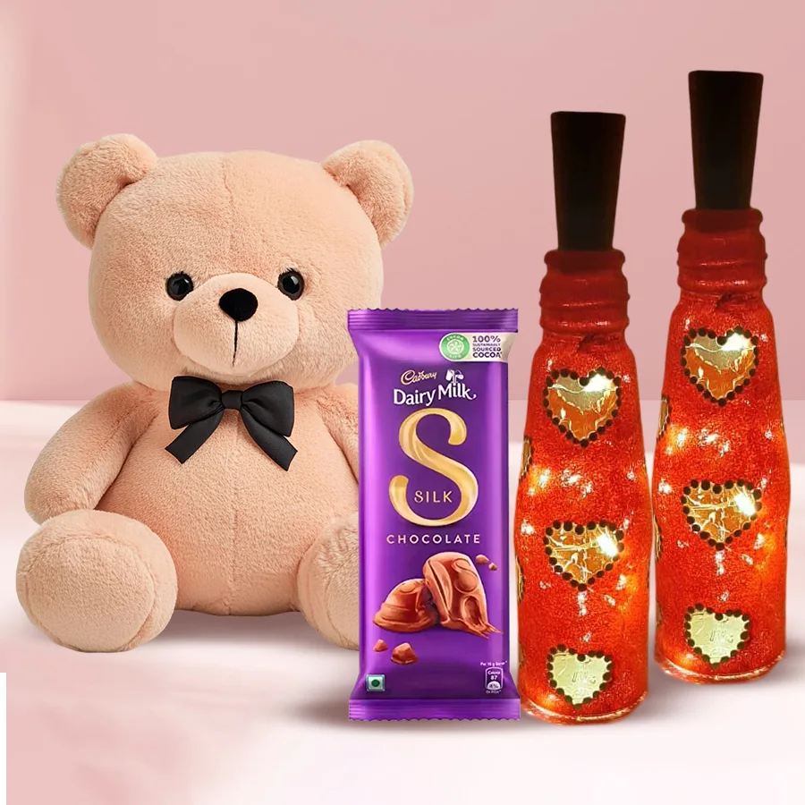 Twin Heart Glow Lamp, 8-inch Love Teddy, and Cadbury Dairy Milk Silk chocolate arranged as a romantic Valentine's gift combo.