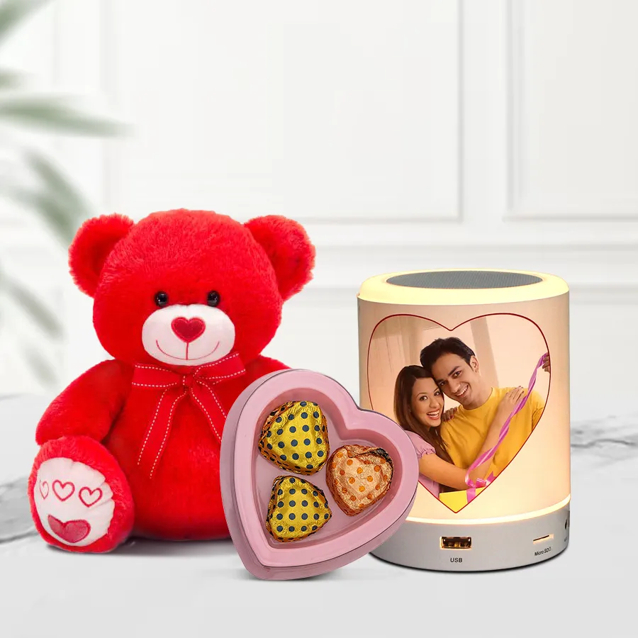 Personalized Bluetooth speaker featuring a favorite photo, accompanied by a red teddy bear and heart-shaped chocolates.
