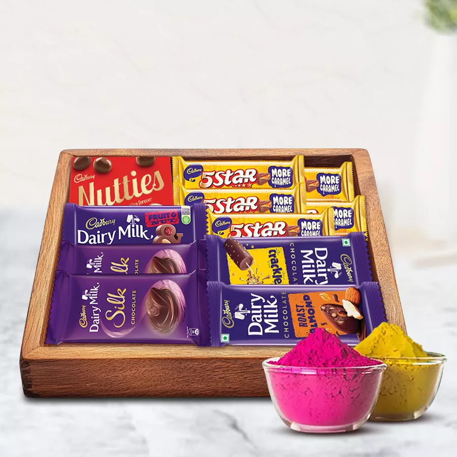Sumptuous mixed chocolates gift tray featuring Cadbury classics like Dairy Milk Silk and Fruit n Nut, elegantly arranged on a wooden tray with vibrant herbal gulal for Holi celebrations.