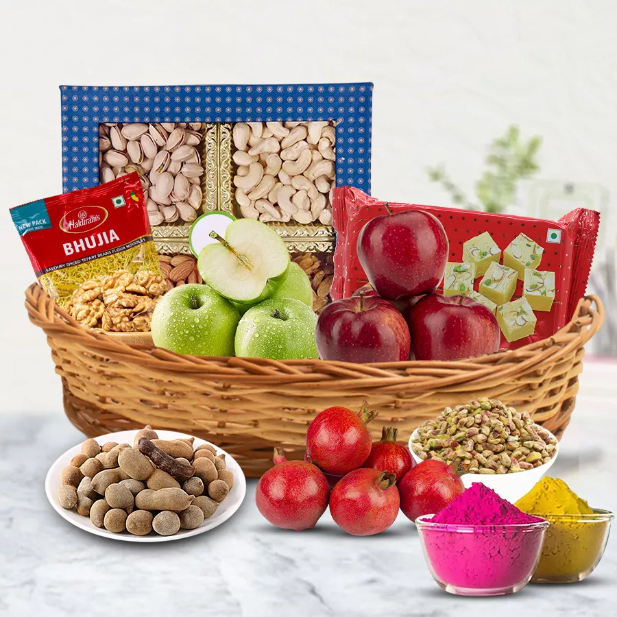 A beautifully arranged cane basket filled with fresh fruits, nuts, Haldiram's sweets, and colorful herbal gulal for Holi celebrations.