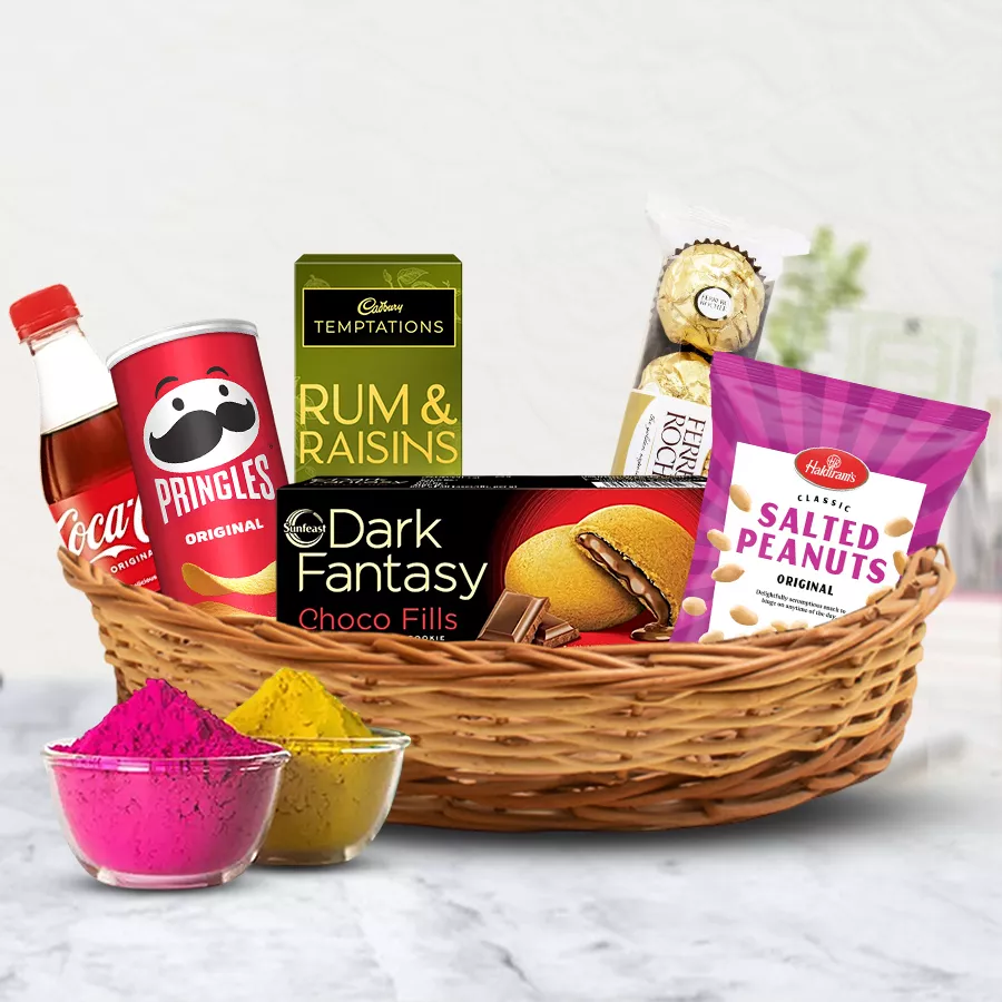 Sumptuous Snacks Gift Hamper featuring Pringle Chips, ITC Dark Fantasy Biscuits, salted peanuts, Coca Cola, Cadbury Temptation Rum n Raisins, Ferrero Rocher chocolates, and vibrant herbal gulal in a small basket for Holi celebration.