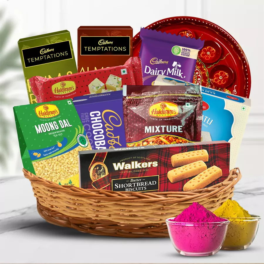 Cane basket filled with assorted snacks, sweets, a designer pooja thali, and herbal gulal for Holi celebrations