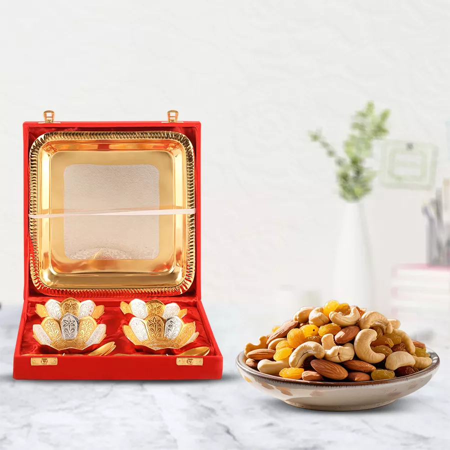 Decorative silver bowl gift set with crunchy dry fruits in a vibrant red bowl placed on a textured surface.