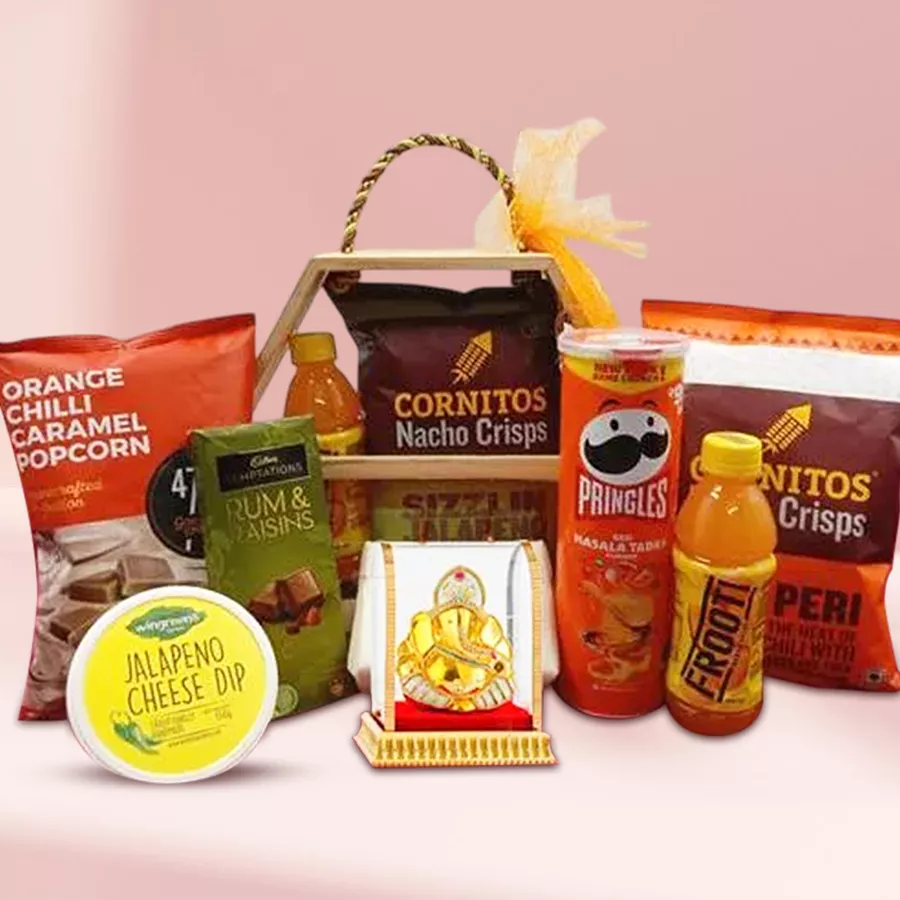 Bountiful Snacks and Chocolate Hamper with Vighnesh Idol presented in a wooden hexagonal basket, featuring Pringles, Cornitos Nachos, Himalayan Salt Caramel Popcorn, Wingreens Cheese Dip, Cadbury Temptation chocolates, and Parle Fruity bottles.