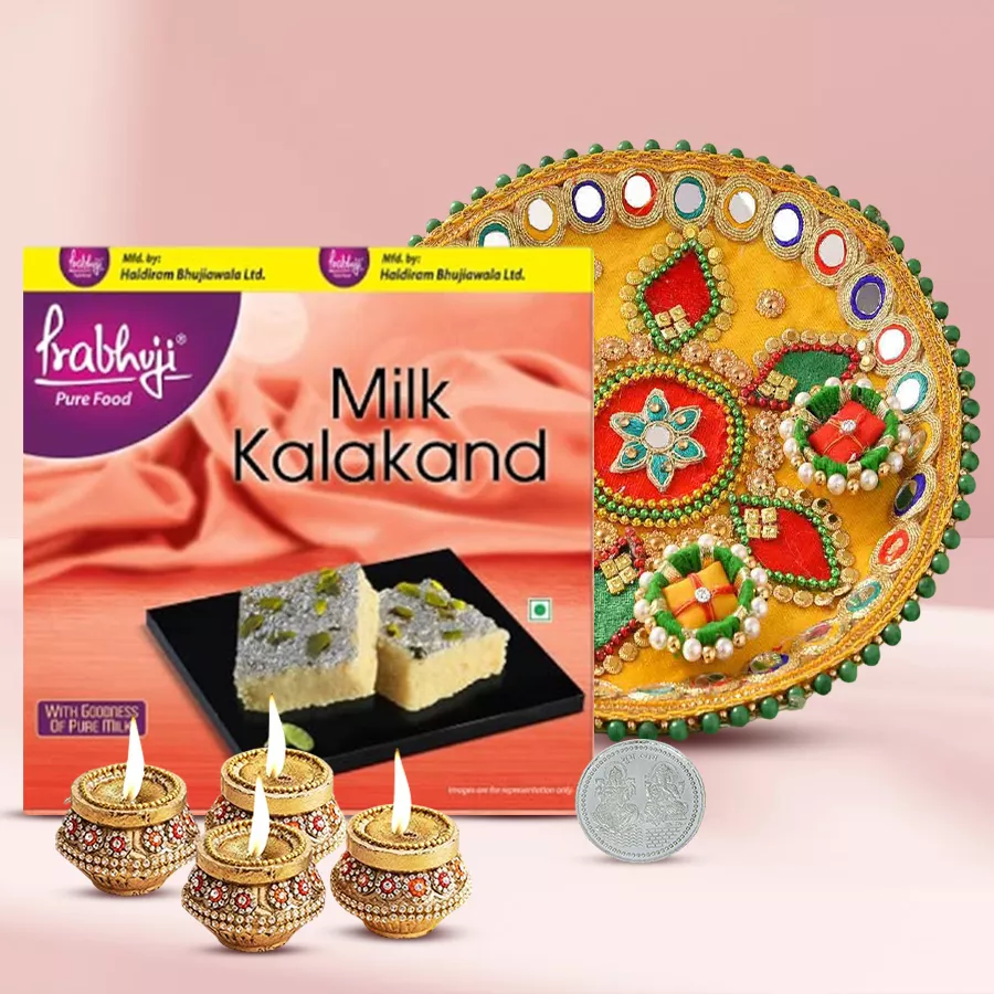Blissful selection of Haldiram sweets, terracotta diyas, stylish steel thali, and silver-plated Laxmi Ganesh coin arranged for Diwali celebration.