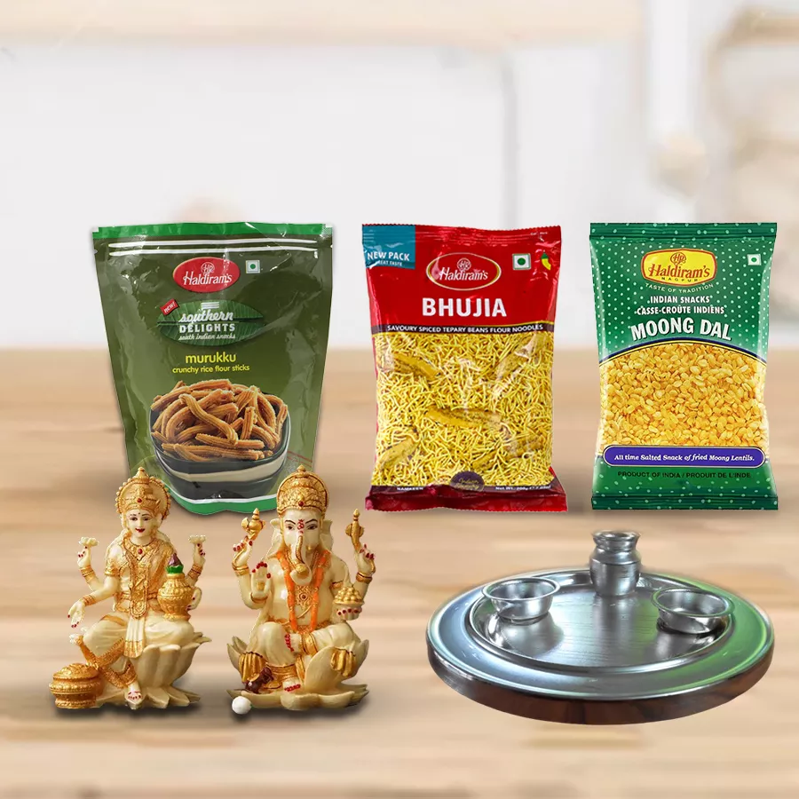 Classic Puja Thali with silver plating, Haldirams snacks mix including Bhujia, Moong Dal Fried, and Murrukku, a Laxmi Ganesh idol, and two diyas for Diwali celebrations.