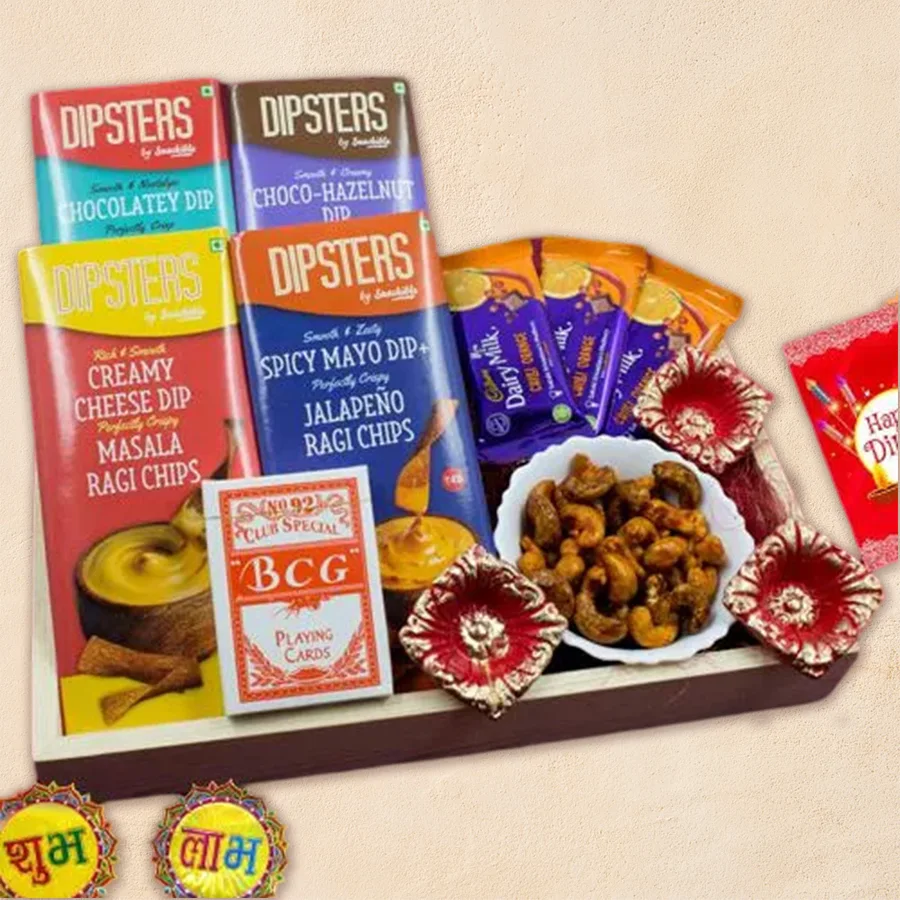 Famous Teen Patti Game Night Combo with wooden tray, Cadbury Dairy Milk Chilli Orange chocolates, Dipsters chips and dips, masala cashews, mini biscuits with choco-hazelnut dip, two decorated diyas, and a deck of playing cards.