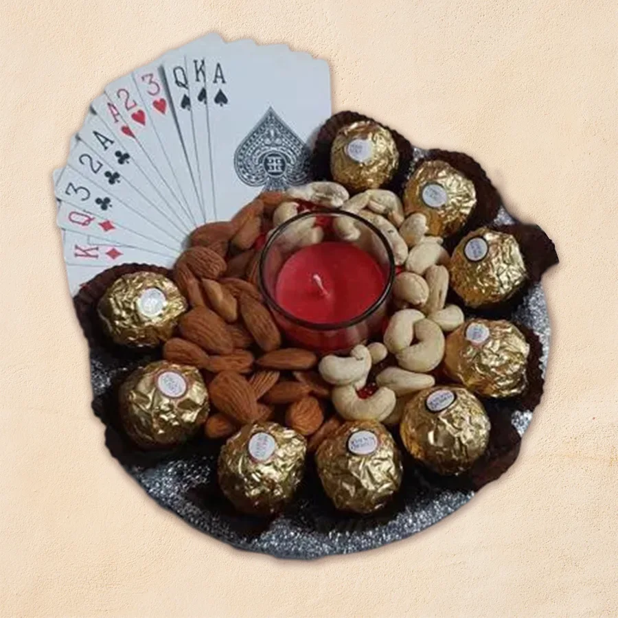Teen Patti Combo hamper featuring Ferrero Rocher chocolates, crunchy almonds, salted cashews, an Iris aroma candle in a shot glass, vibrant playing cards, and a stylish steel thali, presented for Diwali celebrations.