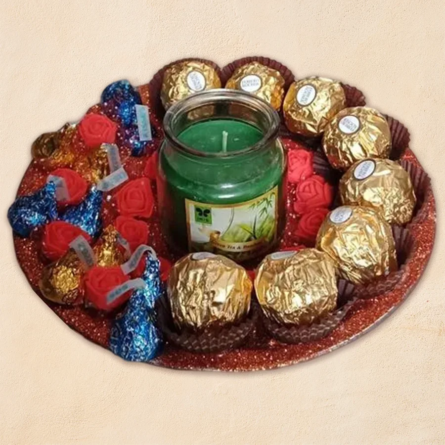 Marvelous gift platter featuring Ferrero Rocher, Hershey's Kisses, and an aroma candle on a stainless steel thali decorated with art flowers.