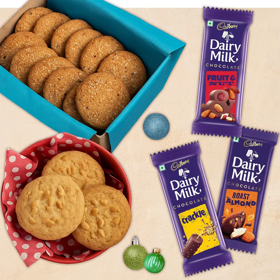A festive assortment of chocolates and cookies including Cashew Cookies, Brandy Snap Cookies, and three Cadbury Dairy Milk bars in holiday packaging.