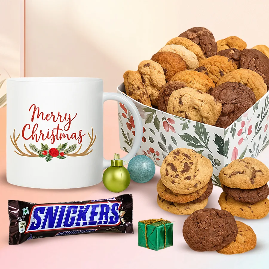 A festive gift tin filled with assorted cookies, a Snickers chocolate bar, and a personalized Merry Christmas mug.