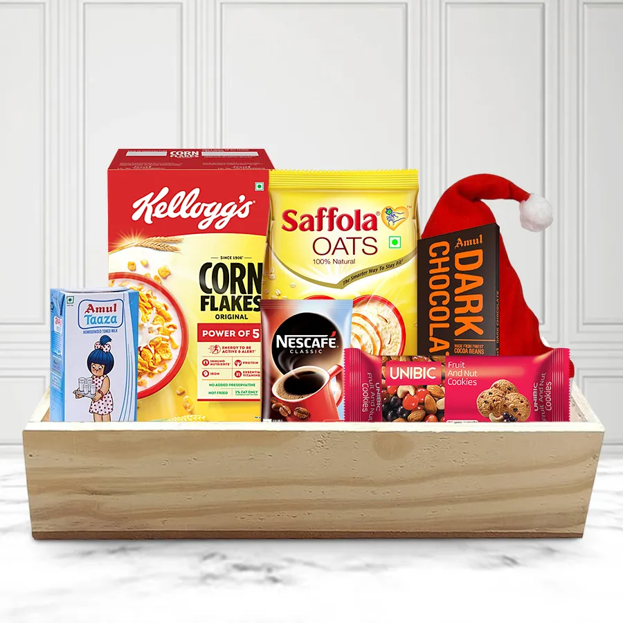 Classy Holiday Breakfast Hamper featuring Kellogg’s Corn Flakes, Amul Toned Milk, Nestle Nescafe Classic Coffee, UNIBIC Fruit and Nut Cookies, Saffola Oats, Amul Dark Chocolate, a Merry Christmas cap, and a wooden tray.
