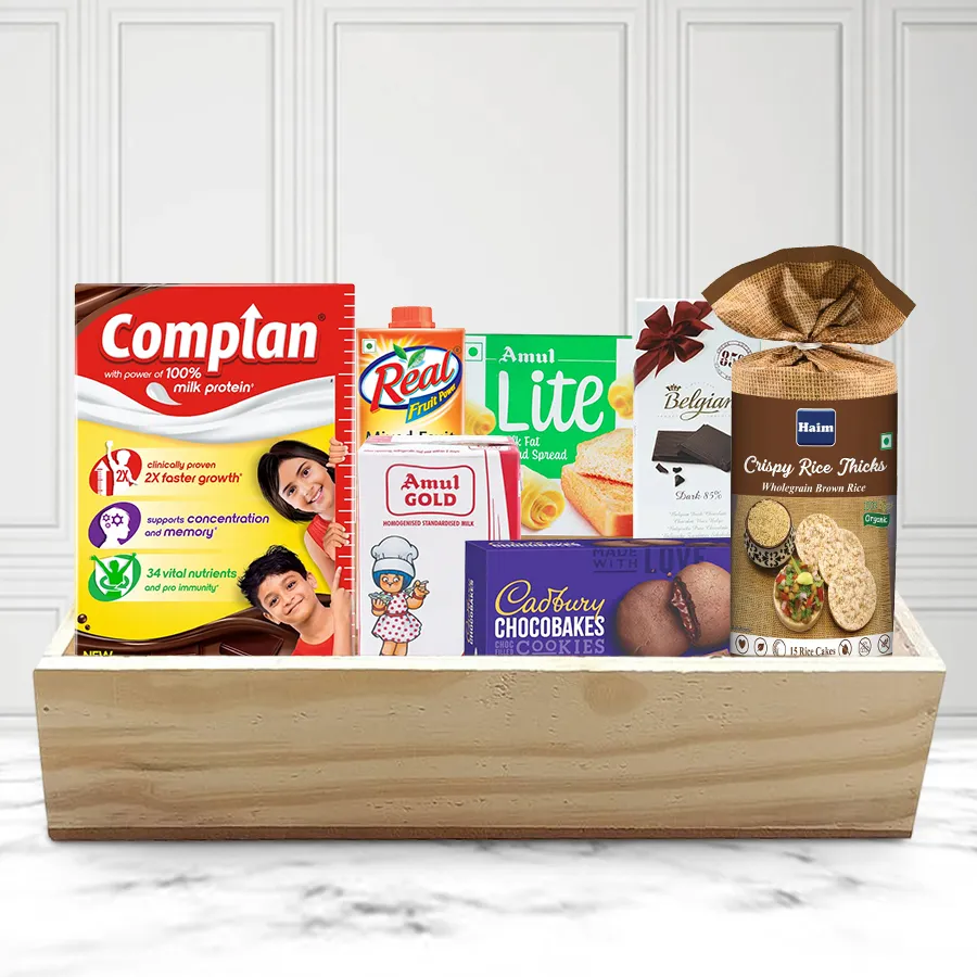 Christmas Breakfast Hamper arranged on a wooden tray featuring chocolate drink, rice cakes, juice, spread, and chocolates.