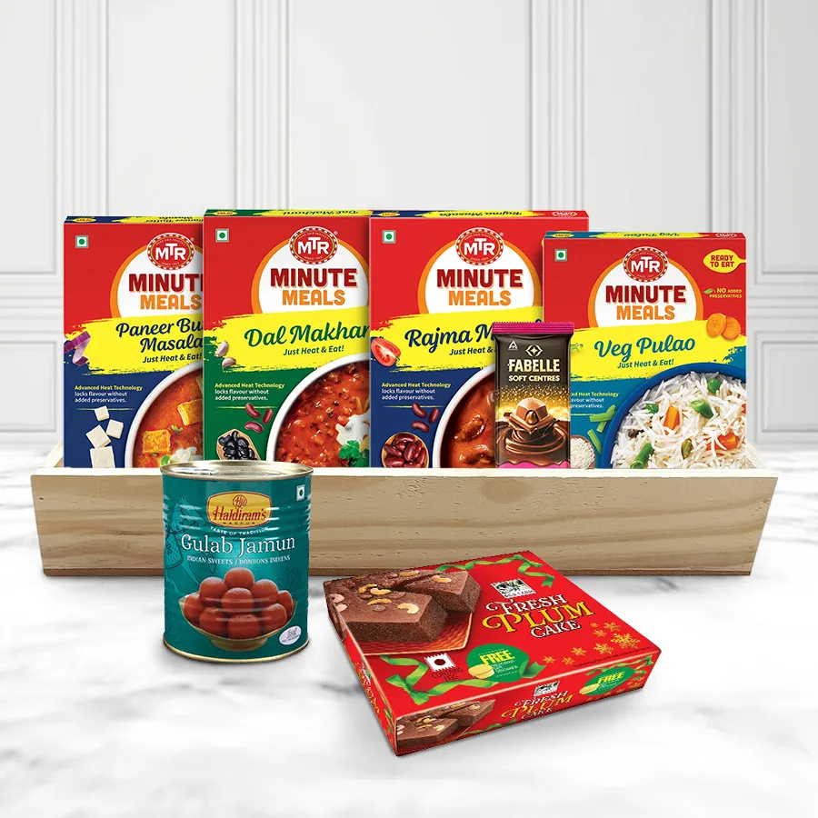 A beautifully arranged wooden tray filled with a variety of vegetarian dishes, including Paneer Butter Masala, Dal Makhani, Rajma Masala, Vegetable Pulao, Haldiram’s Gulab Jamun, Biskfarm Plum Cake, and Fabelle Choco Mousse bars, designed for a festive Christmas lunch.