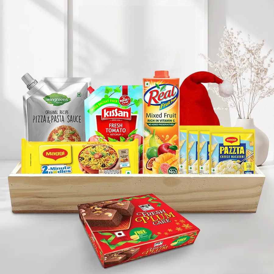 Sensational Breakfast Hamper filled with festive treats including noodles, ketchup, macaroni, sauce, juice, plum cake, a Merry Christmas cap, and a wooden tray.