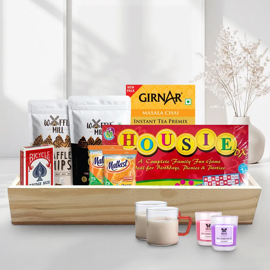 Christmas Evening Snacks Hamper featuring Girnar Masala Tea, Borosil mugs, Malkist cheese crackers, Waffle Mill chips, playing cards, Housie, candles, and a wooden tray.