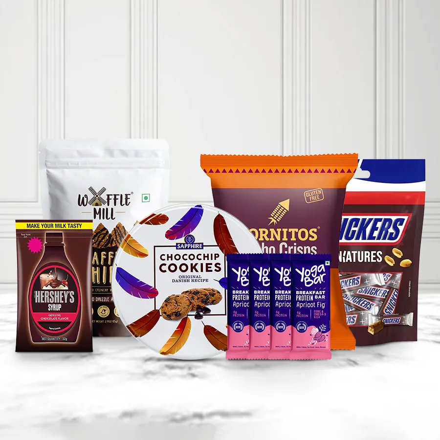 Special Choco Delight Hamper featuring waffle chocolate chips, Cornitos nachos, mini Snickers bars, chocolate syrup, Kravour cookies, and Yoga protein bars in a festive arrangement.