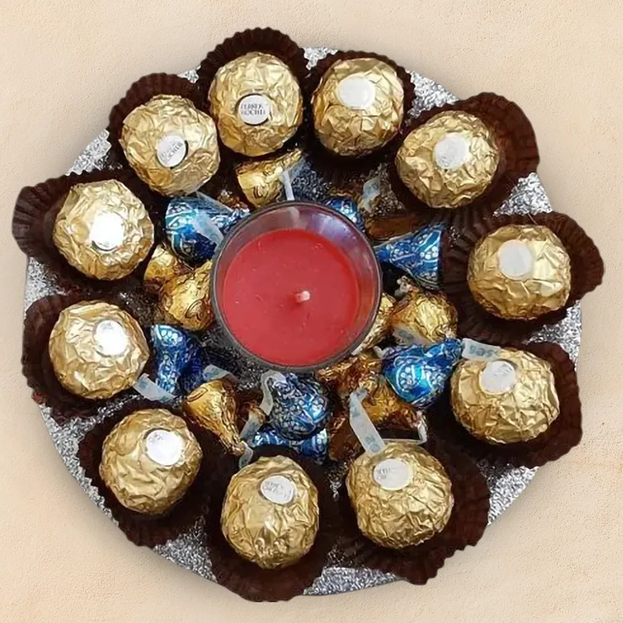 Hershey's Kisses Cookie 'n' Cream chocolates, Ferrero Rocher chocolates, aroma candles, and a decorative plate arranged as a gift set.