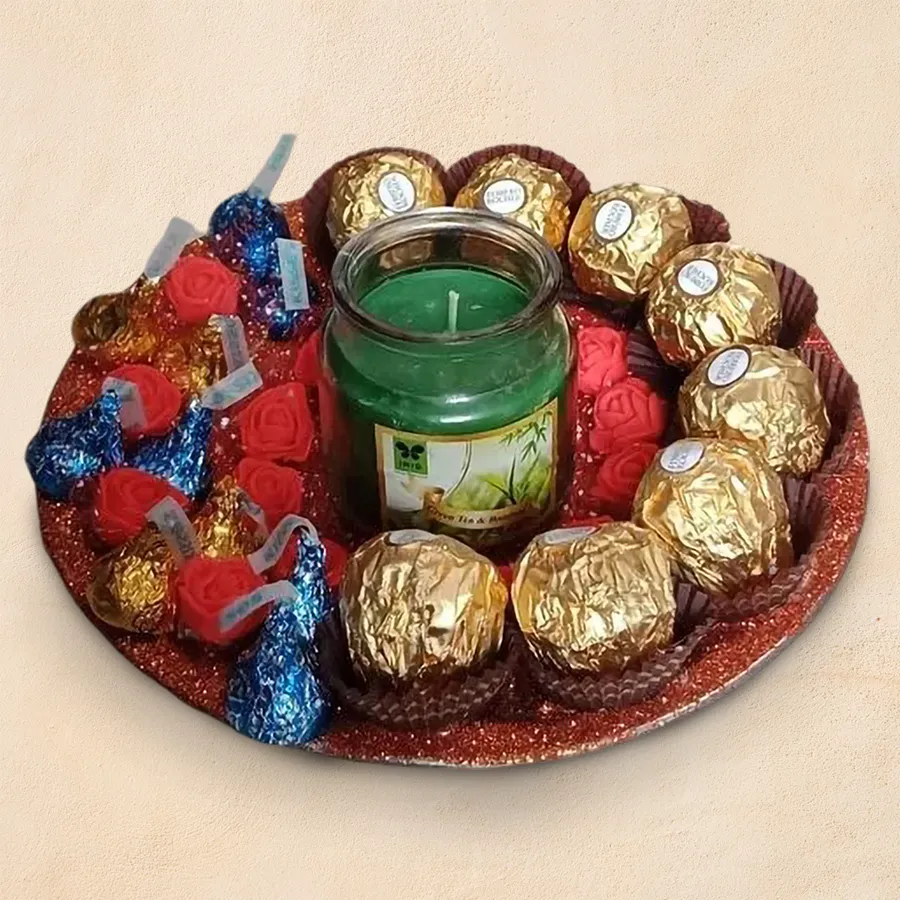 Elegant gift plate featuring Ferrero Rocher chocolates, Hershey’s Kisses Cookies n Cream, a scented candle, and decorative flowers.